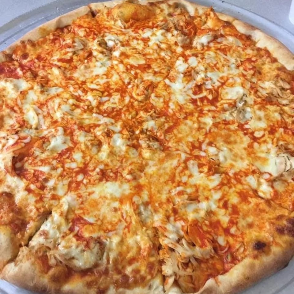 A whole, sliced Bravo Pizza with melted cheese and red sauce, ready to eat.