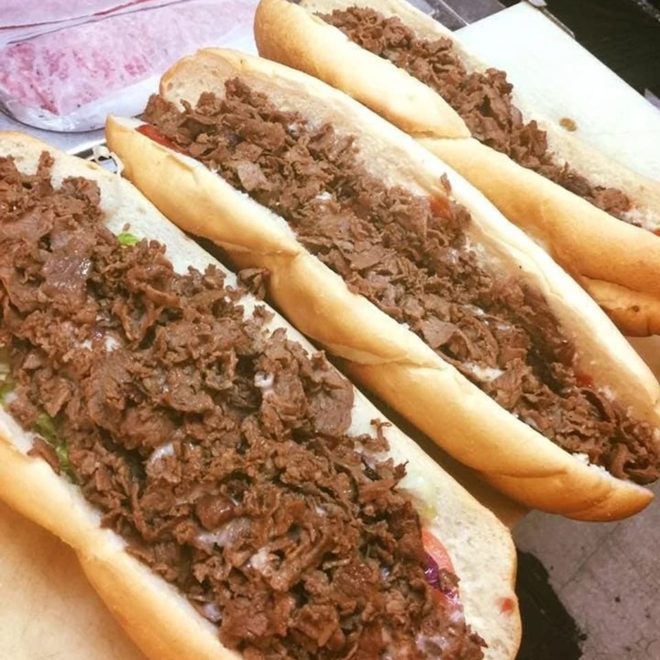 Four hearty cheesesteak sandwiches, overflowing with thinly sliced meat and melted cheese, ready to be served.